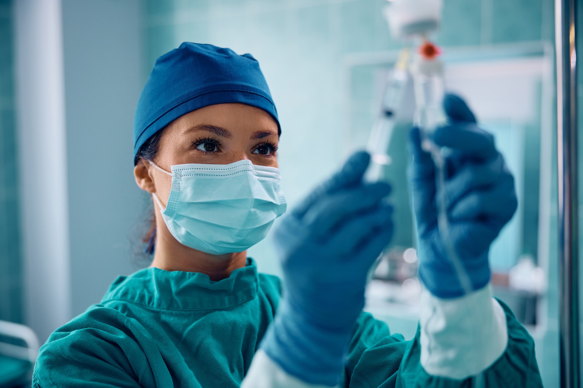 Surgical nurse injecting medicine through IV drip in operating room.